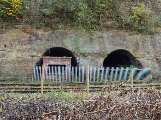 Two tunnel openings in sandstone wall beside railway tracks at Edge Hill