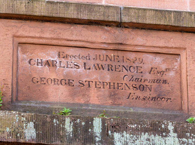 Close-up of an engraved stone plaque dated 1829, referencing George Stephenson and railway construction.