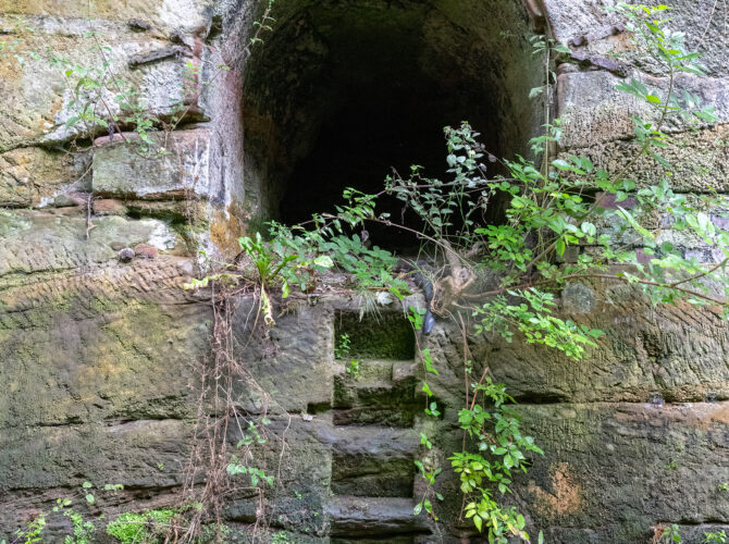 Narrow arched opening and stone steps set into the sandstone wall