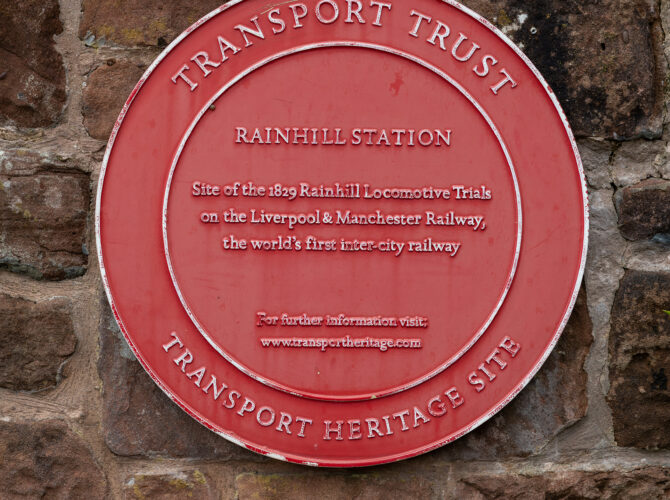 Red circular plaque identifying Rainhill station as the site of the 1829 locomotive trials.
