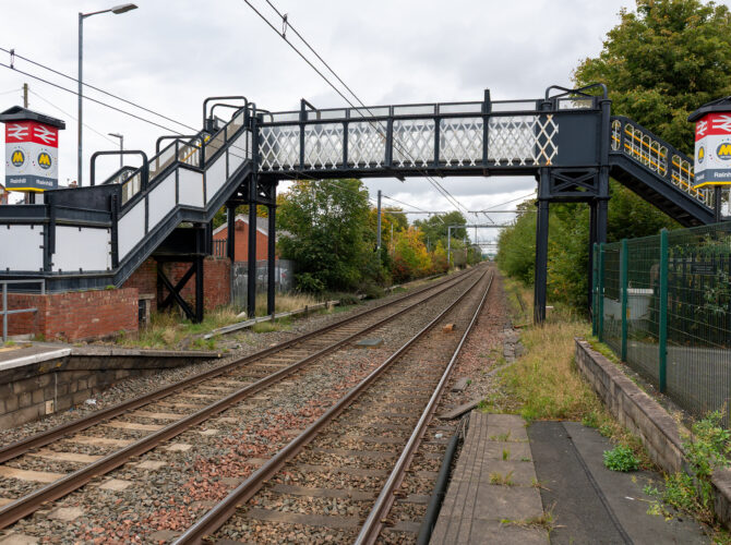 View of railway footbridge spanning the tracks from Rainhill station platform.