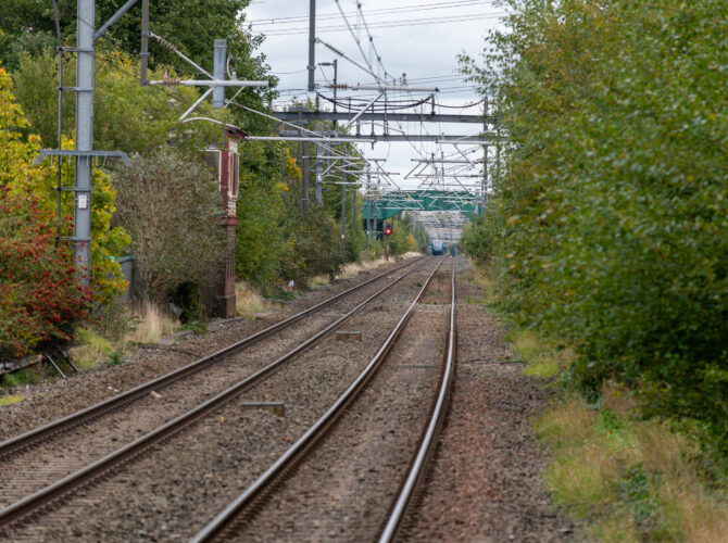 Long straight railway line at Rainhill with train in the distance.