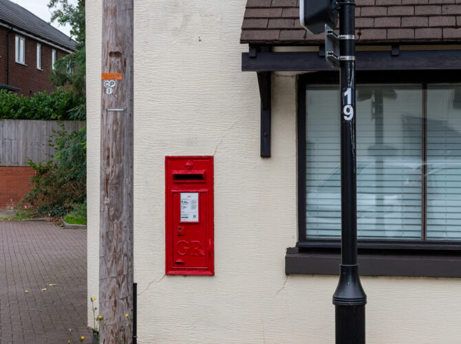 Street corner with Manchester Row sign and a traditional wall-mounted post box.