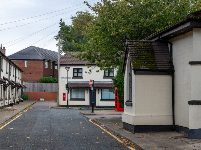 View along the village street showing workers’ cottages and a traditional red phone box.