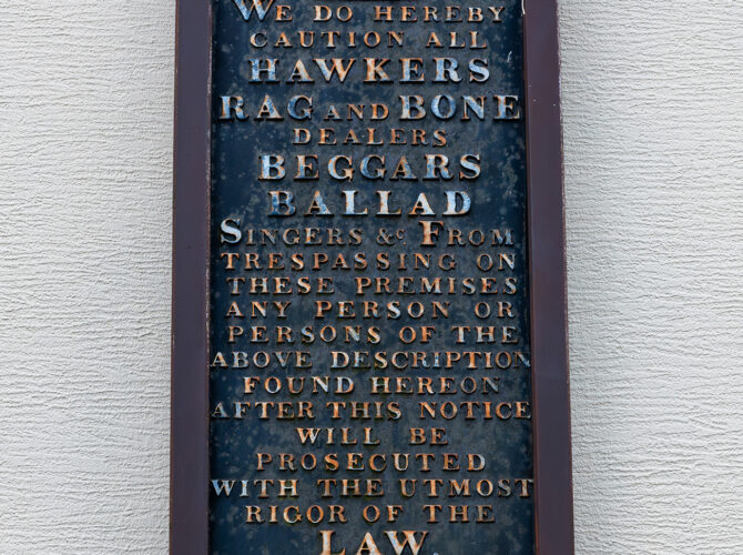Close-up of the historic plaque warning hawkers and traders not to enter the village.