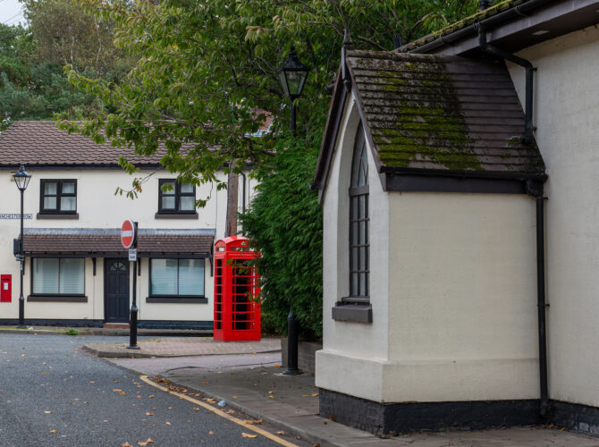 A traditional red telephone box stands beside historic cottages in Vulcan Village