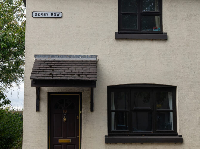A cottage end bearing the street name Derby Row reflects the railway-inspired naming of streets within the village