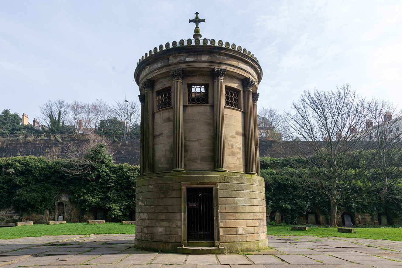 The circular structure features columns and a small gated entrance at ground level.
