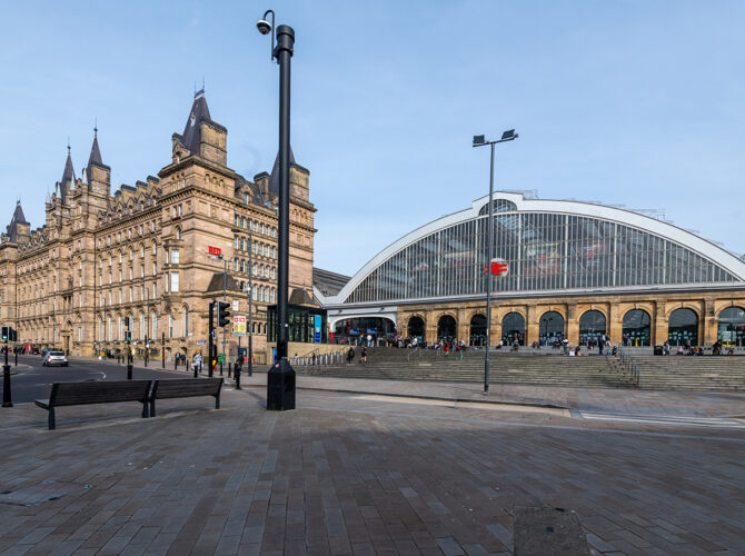 The station’s arched glass frontage sits beside the ornate North Western Hotel, with steps and people gathered outside.