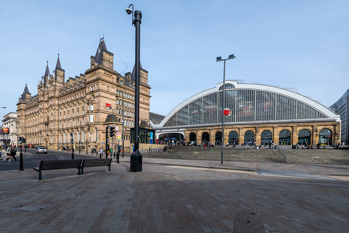 The station’s arched glass frontage sits beside the ornate North Western Hotel, with steps and people gathered outside.