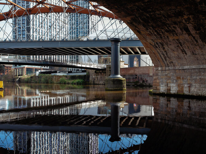 Original viaduct arch with a iron column in the river supporting later bridge structures.