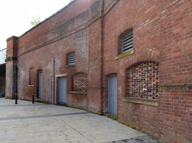 Architectural detail of the arrivals station wall, highlighting vents, brick patterns and stone sills.