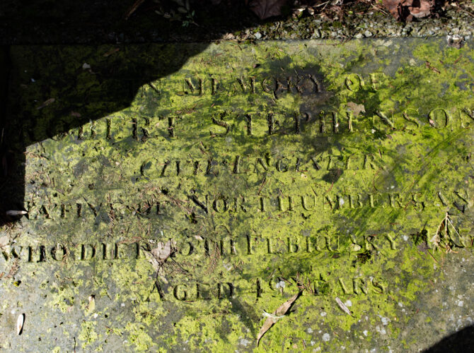Weathered stone marking the grave of Robert Stephenson, partly covered in moss.