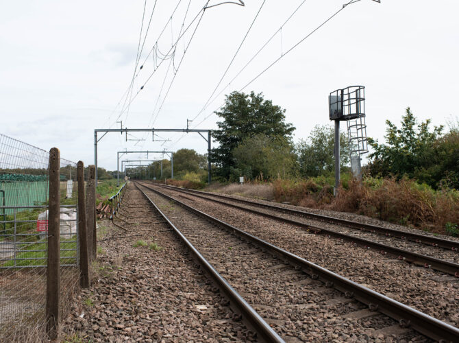 Electrified railway tracks stretching across the flat landscape of Chat Moss.