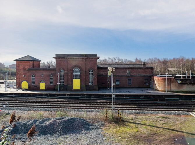 A broad view of Edge Hill Station showing the original brick and stone buildings, open platforms and the surrounding railway landscape