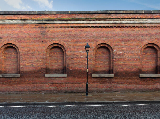 Straight-on view of the Power Hall’s exterior wall, showing evenly spaced arched recesses and historic brick detailing.