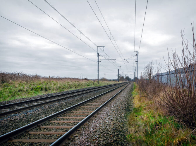 Straight railway tracks crossing the flat mossland landscape of Chat Moss.