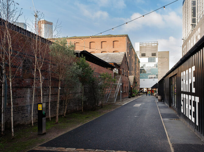 View along Grape Street with the historic brick warehouse on one side and modern units opposite, showing the blend of old industrial and new development.