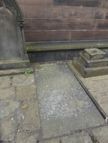Memorial structure and worn stonework at Stephenson’s grave, set against the church exterior.