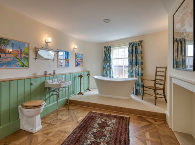 Restored interior featuring a freestanding bath, tiled floor, and period-style fittings within the historic house.