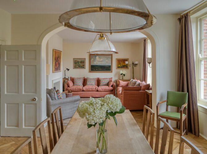 Comfortable living space with sofas, fireplace, and large windows, blending historic features.
