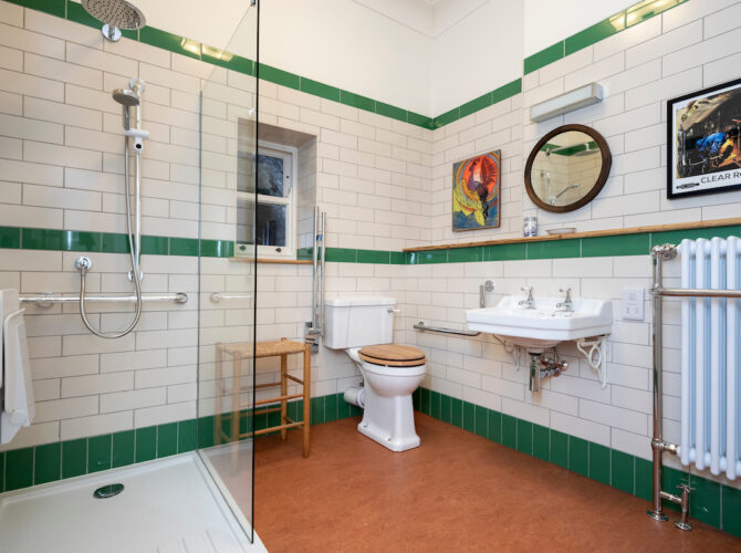 Larger bathroom space with white and green tiling, shower enclosure, and period-style fittings.