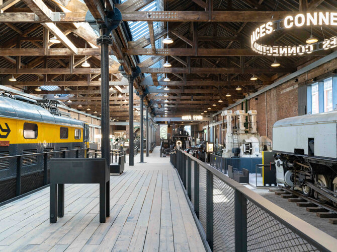 View along the gallery with rows of preserved engines and mechanical equipment arranged on either side of a raised walkway.