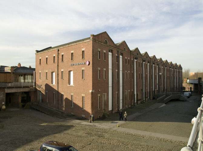 Close view of the building’s brickwork, arched doorways and loading points where goods once moved between trains and storage.