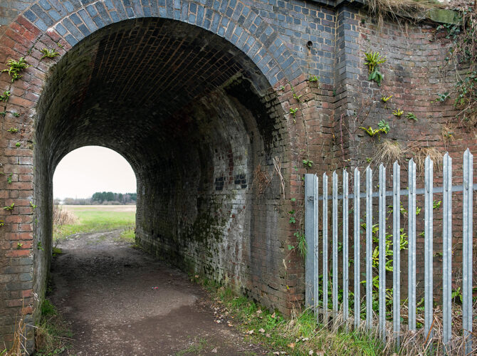 Inside the tunnel, the curved brick ceiling frames a view out to fields on the far side.