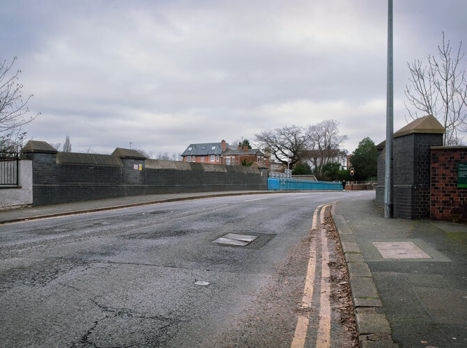 Approach to Monks’ Hall Bridge showing roadside walls and railings that mark the crossing over the railway.