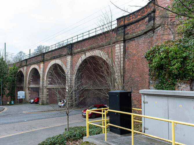 View along the viaduct line showing repeating arches, roadside setting and modern equipment in the foreground.