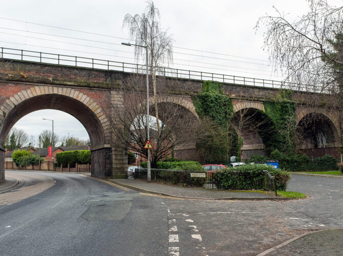 Brick railway viaduct with large arches spanning a road in a town setting