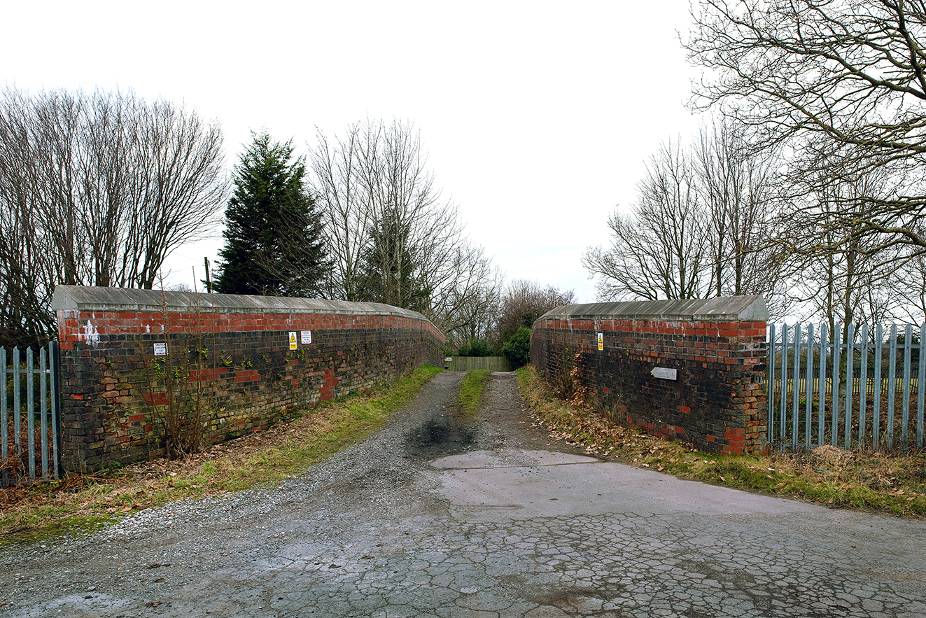 A frontal view looking along the track across Newton’s Bridge, with symmetrical brick parapets on either side. The worn surface and simple construction reflect its long-standing agricultural use.