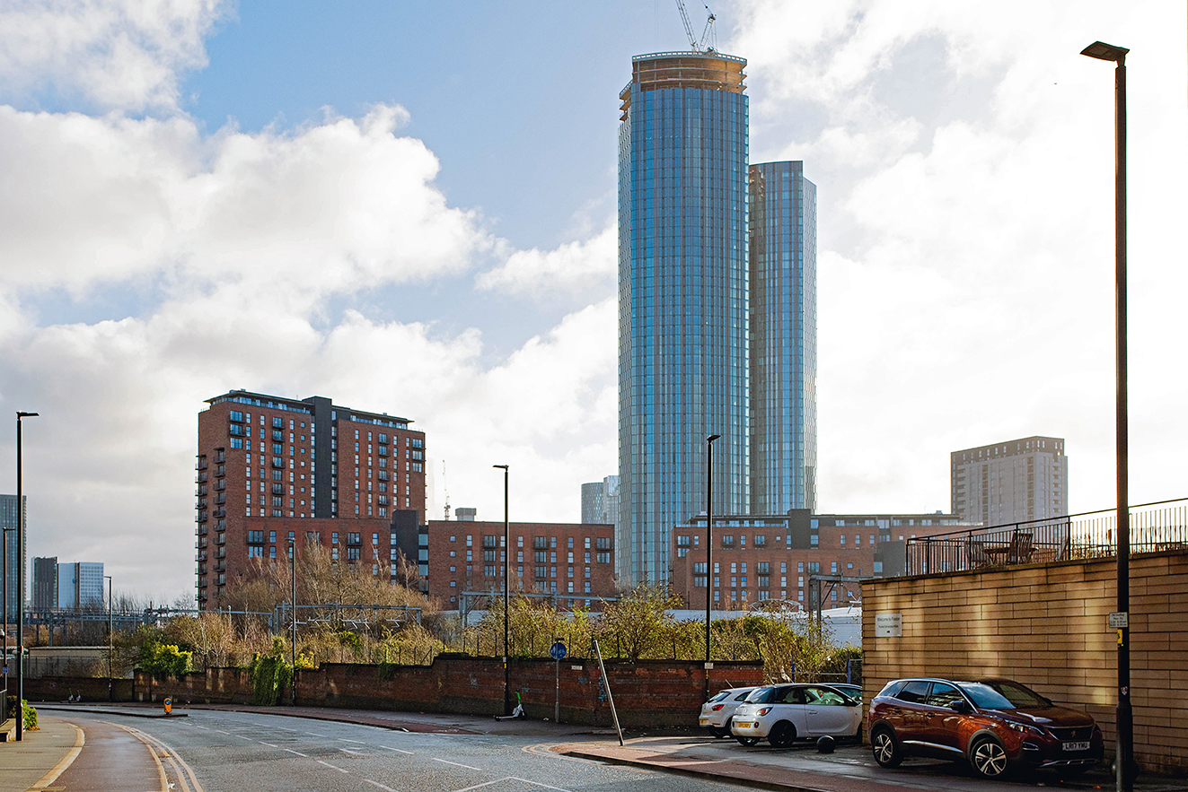 Wide view of the street and wall with high-rise buildings beyond, showing old and new together.