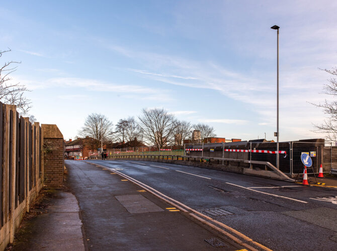 View along the road over the bridge with temporary barriers and fencing along one side