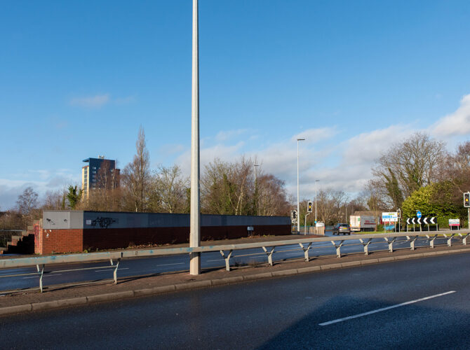 Wide road junction with central barrier and traffic lights.