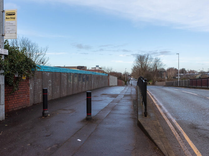 Side view along the bridge approach with pedestrian path and bus stop.