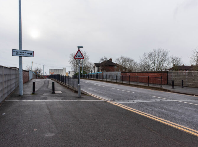 View across the bridge showing the roadway, pavement and modern safety railings.