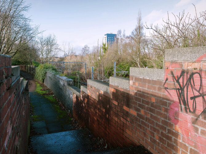 Path descending beside the railway boundary wall.