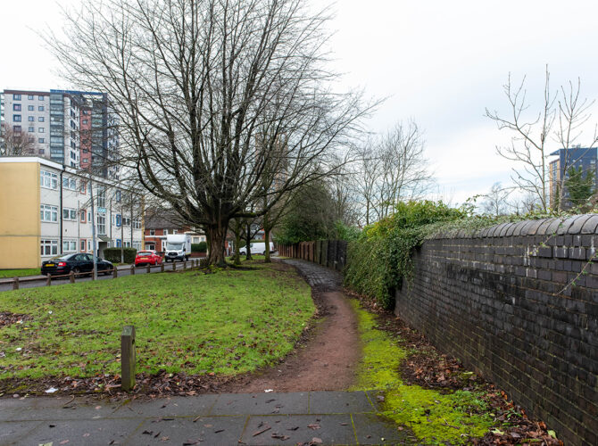 Open view of the surrounding area with path and residential buildings.