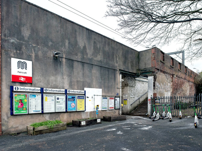 The station entrance on Green Lane, showing modern signage, notice boards and the surviving brick structure beside the steps.