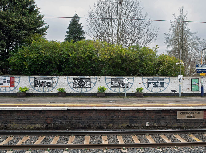A row of illustrated panels mounted on the whitewashed wall, celebrating the area’s railway past.