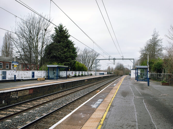 Looking along both platforms with waiting shelters, overhead wires and the line stretching into the distance.