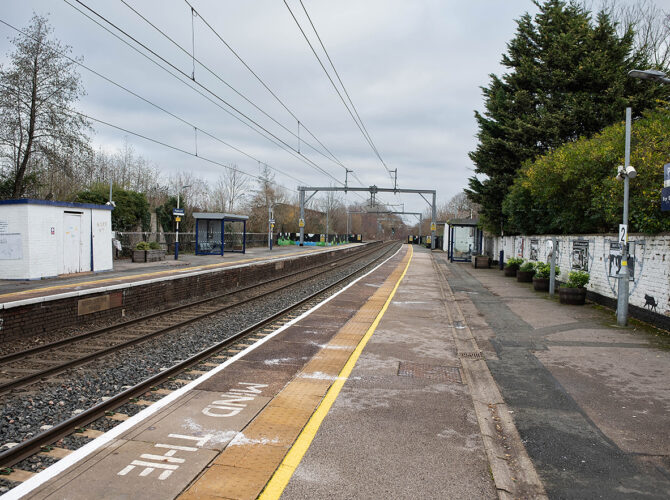 Looking down the platforms with shelters, overhead wires and tracks stretching into the distance