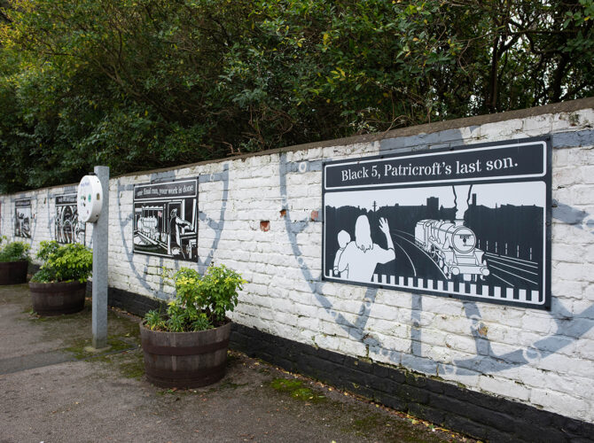 Illustrated panels along a white brick wall telling stories of local railway and engineering history.
