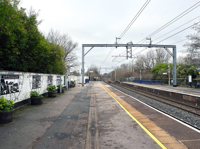 A long view along both platforms, with overhead gantries and the line curving away.