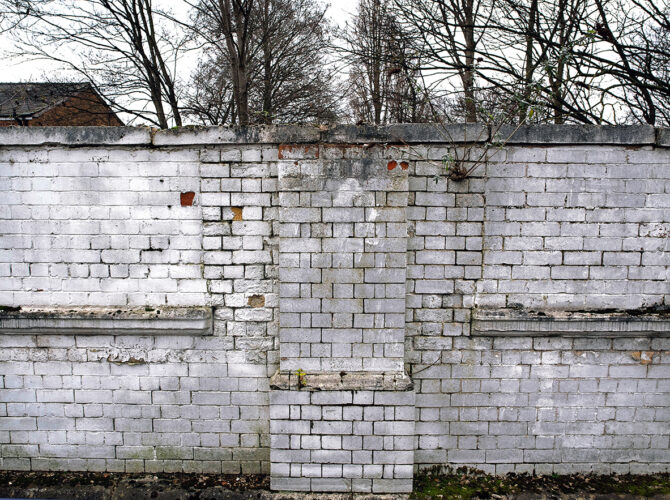 A section of whitewashed brickwork showing a filled-in opening, likely part of the former station or depot structures.