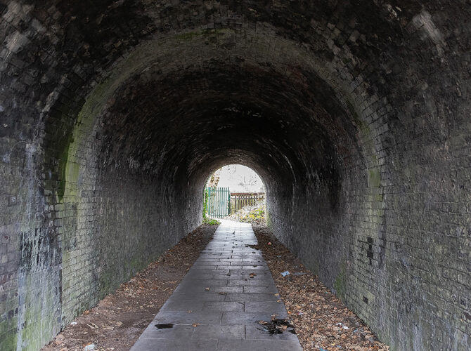 Inside the narrow tunnel, the arched brick ceiling and worn path show years of use.