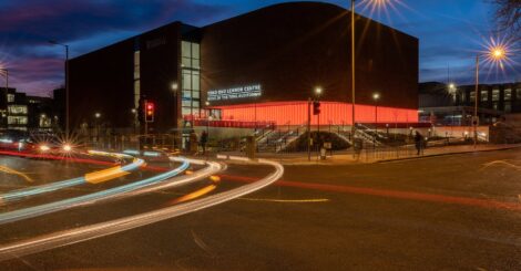 A picture of the Tung Auditorium at night set against a dusk blue sky