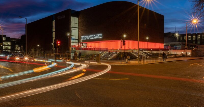 A picture of the Tung Auditorium at night set against a dusk blue sky